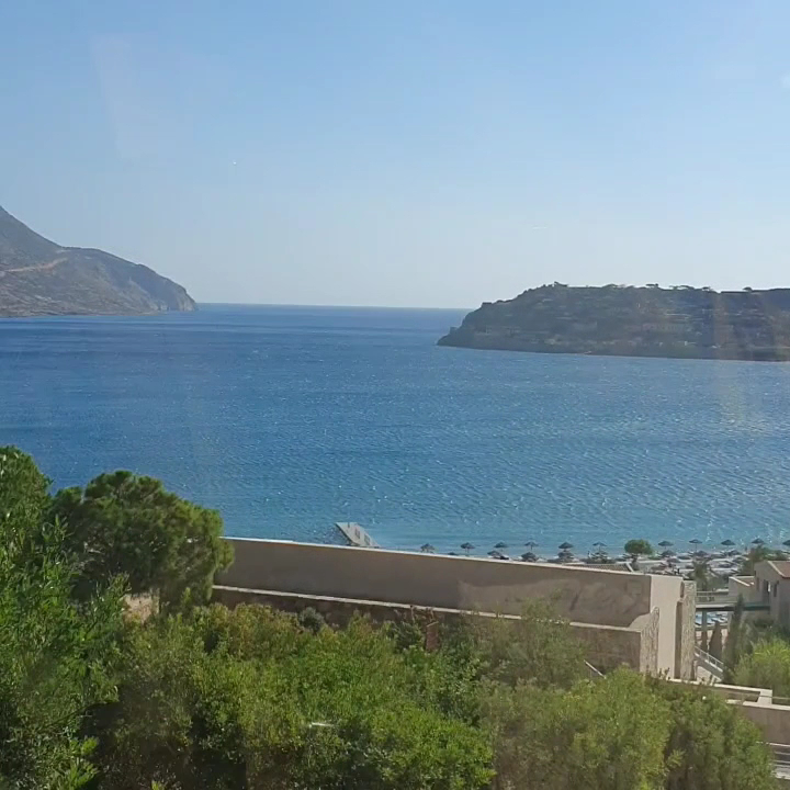 Phaea Blue viesnīcas teritorija ar skatu uz pludmali, saulessargiem un Spinalongas salu tālumā