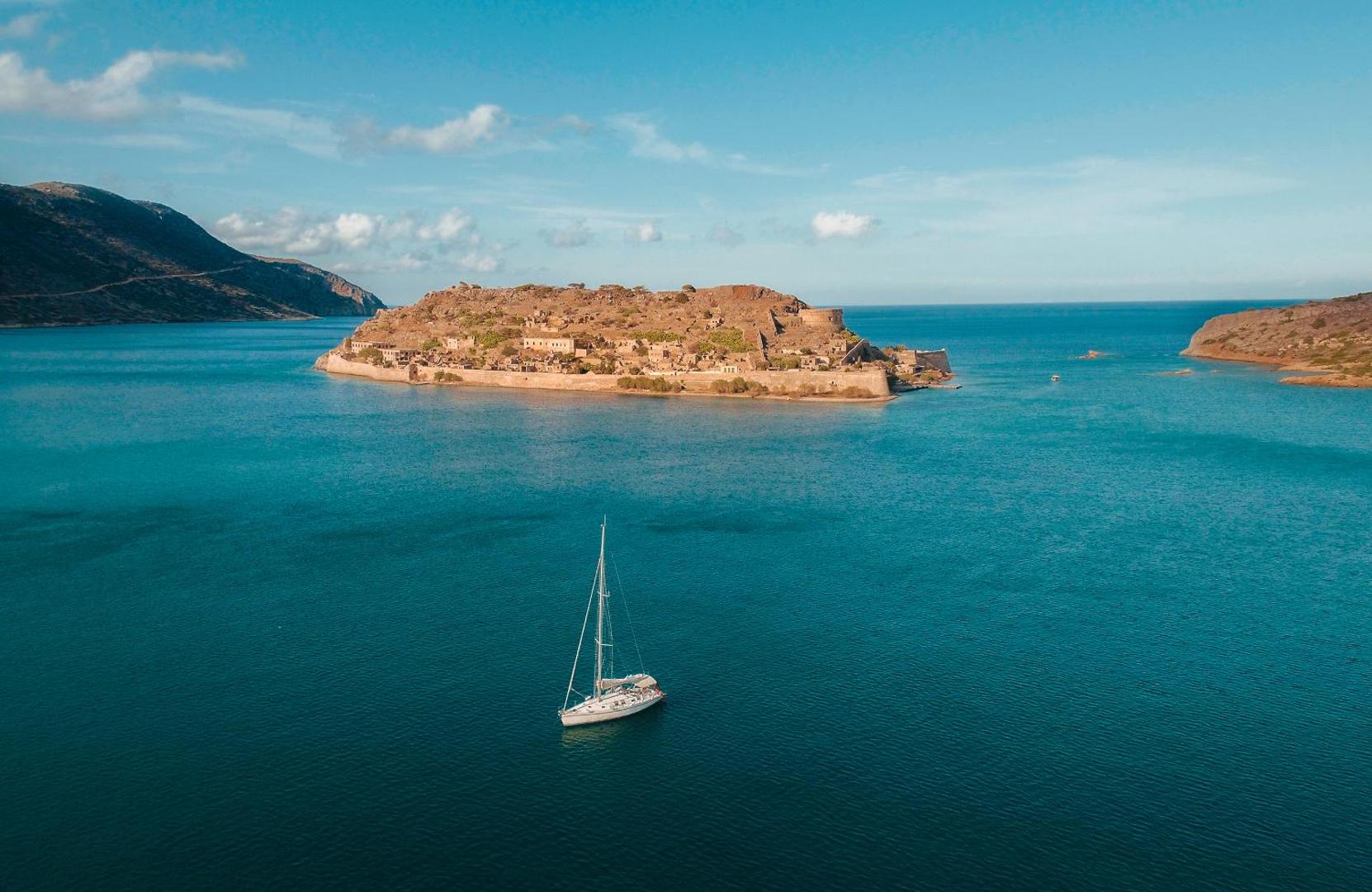 Phaea Blue skats no augšas uz Spinalongas salu un jahtu zilajos Elundas līča ūdeņos Krētā saulainā dienā