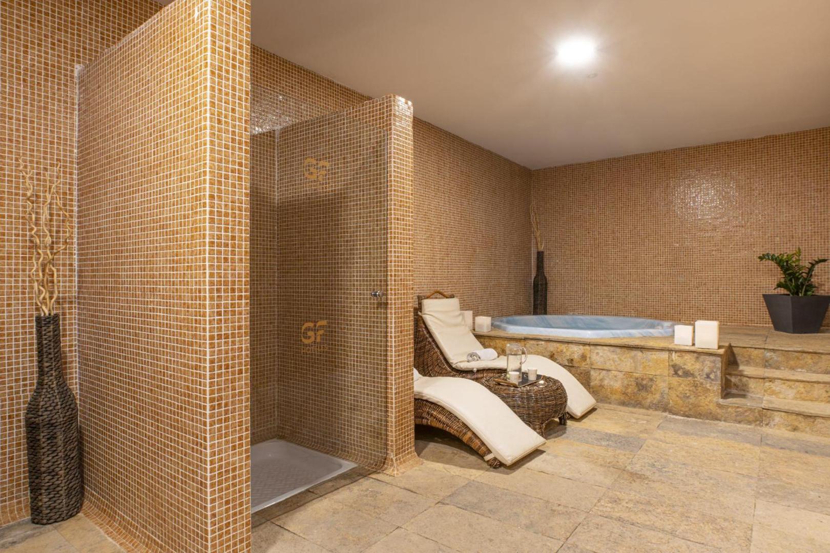 GF Fañabe spa zona ar džakuzi, atpūtas krēsliem un mozaīkas flīžu sienām relaksācijai Tenerifes kūrortā