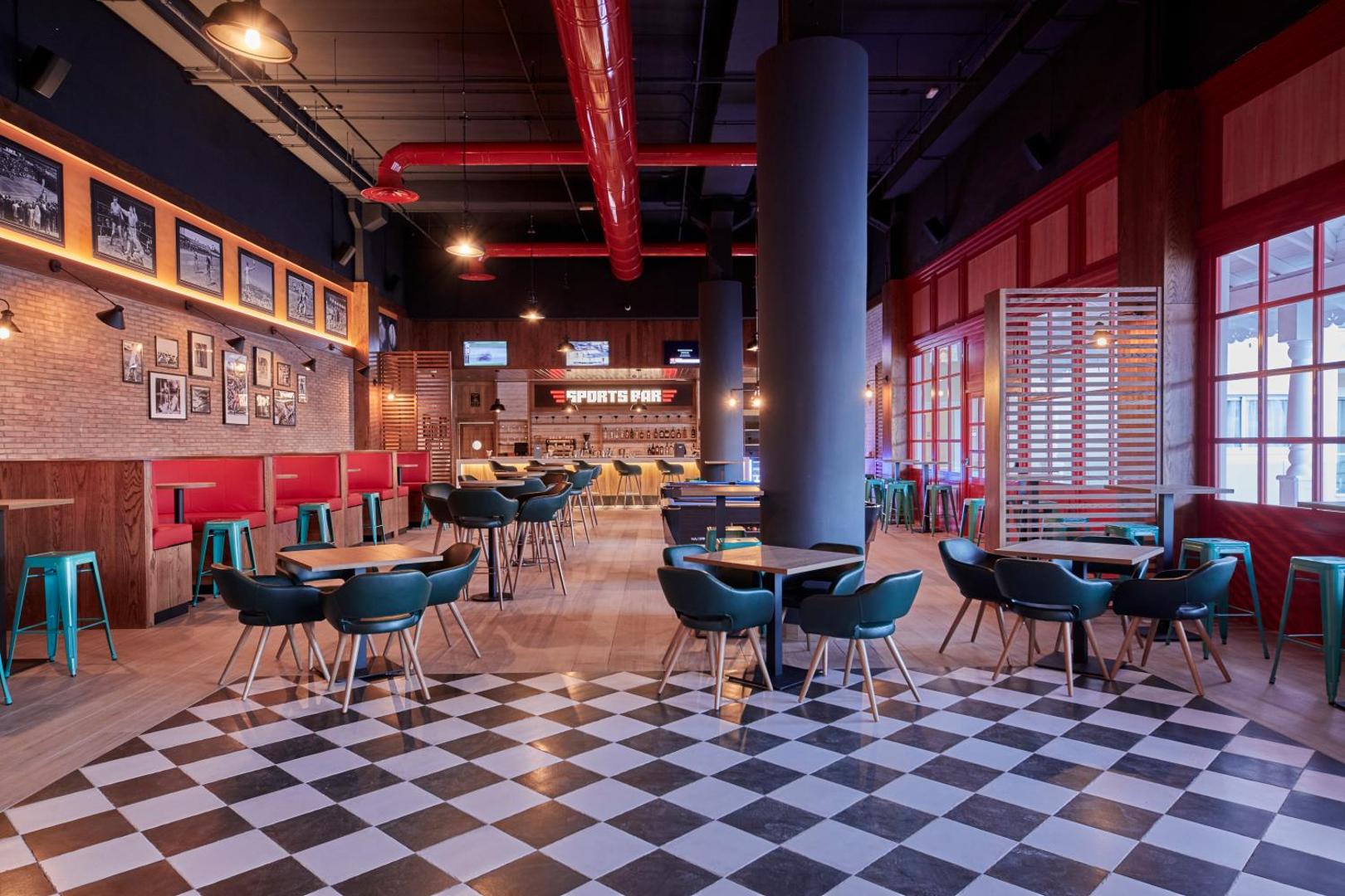 Bahia Principe Fantasia Tenerife sporta bārs ar modernu interjeru, šaha raksta grīdu, sarkaniem akcentiem un TV ekrāniem sporta tiešraidēm.