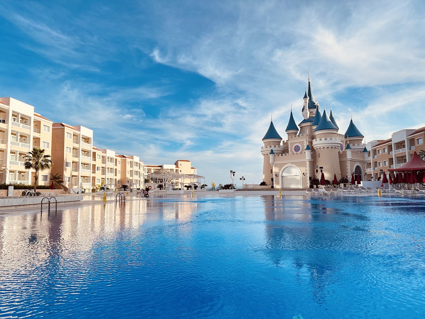 Bahia Principe Fantasia Tenerife lielais āra baseins ar pasaku pili fonā un viesnīcas korpusiem saulainā dienā Tenerifes dienvidos