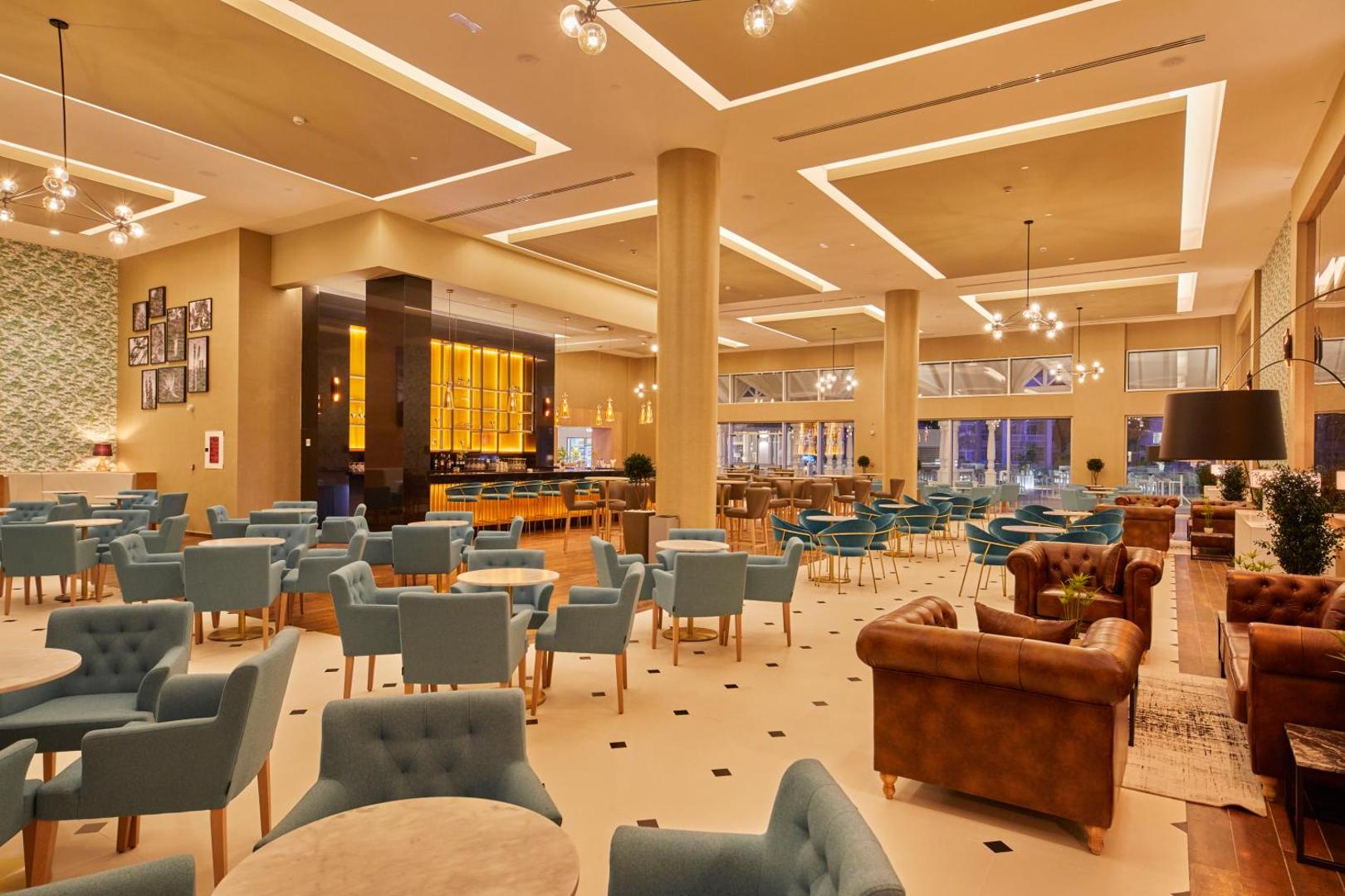 Bahia Principe Fantasia Tenerife viesnīcas plašais lobijs ar modernām mēbelēm, bāru un atpūtas zonu siltos toņos Tenerifes dienvidos