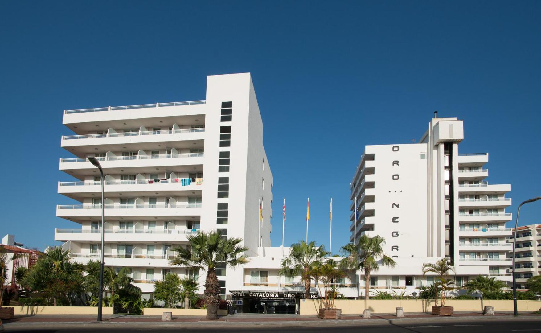 Viesnīcas Catalonia Oro Negro modernā ēka Tenerifē ar balkoniem un palmām — skats no ielas puses saulainā dienā