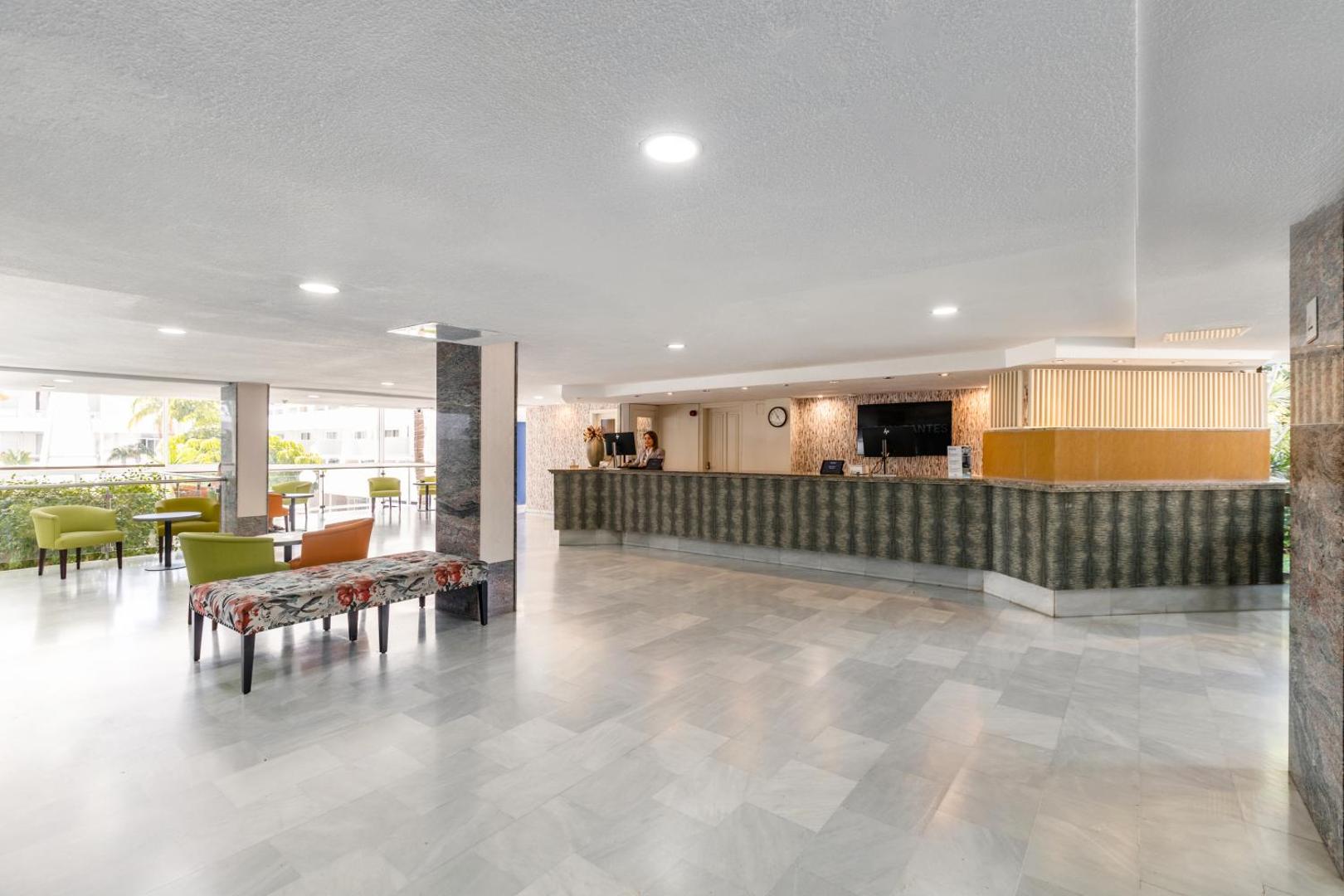 Gaiša un plaša viesnīcas Catalonia Oro Negro recepcijas zona Tenerifē ar modernu leti un atpūtas stūrīti viesu uzņemšanai