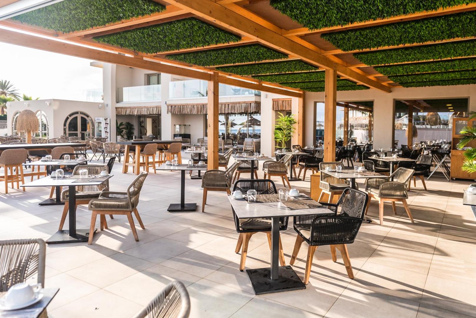 Pepper Sea Club āra terases restorāns ar pītiem krēsliem un koka nojumi, ko rotā zaļumi — skats uz viesnīcas pagalmu