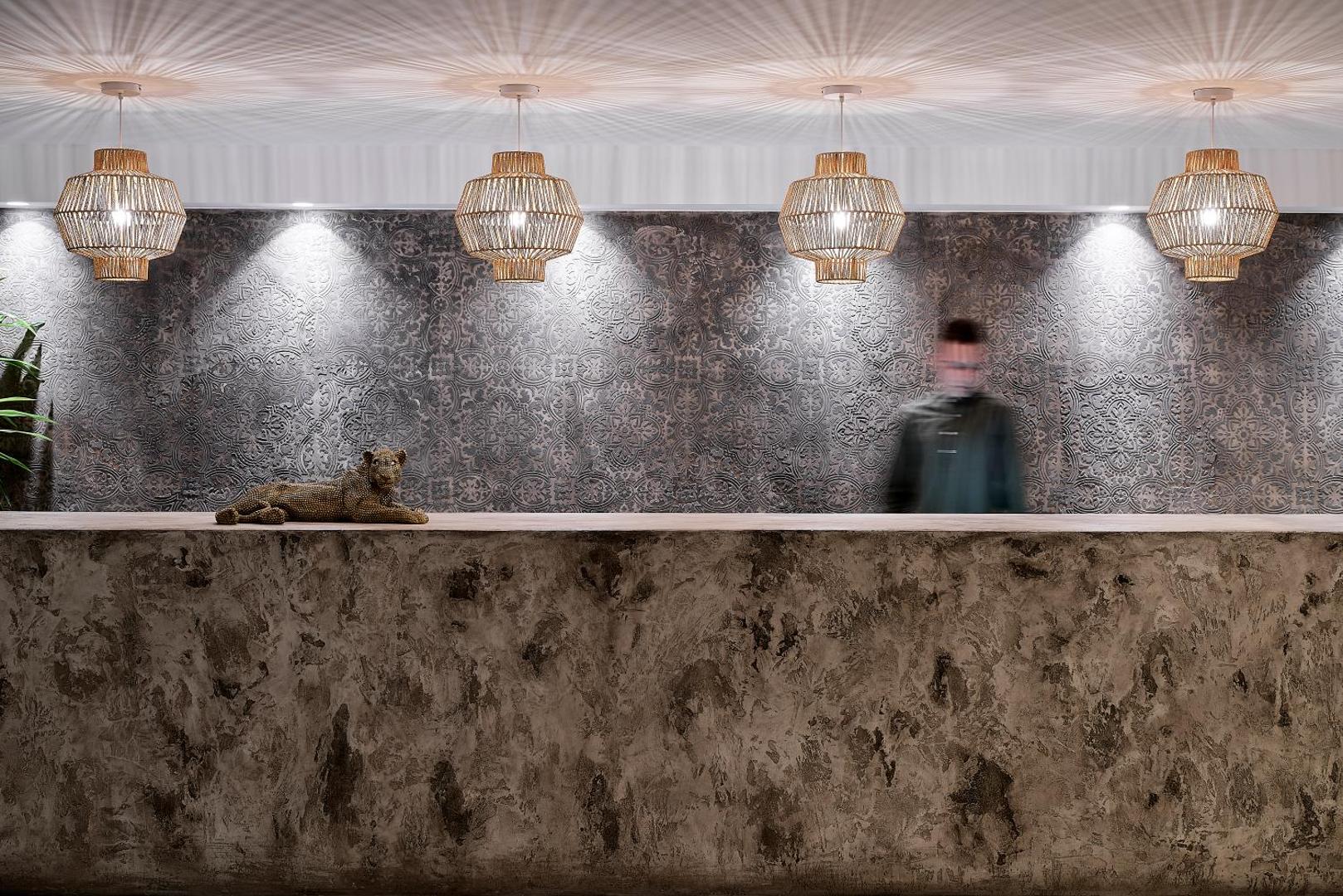 Pepper Sea Club recepcijas lete ar dekoratīvu sienas apdari un pītiem gaismekļiem — moderna un eleganta viesu uzņemšanas zona
