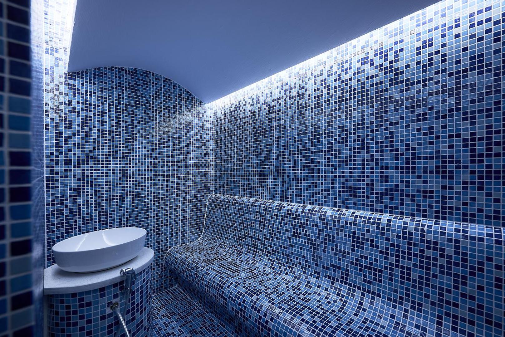 Pepper Sea Club viesnīcas tvaika pirts ar zilām mozaīkas flīzēm un ergonomisku sēdvietu spa centrā Krētā