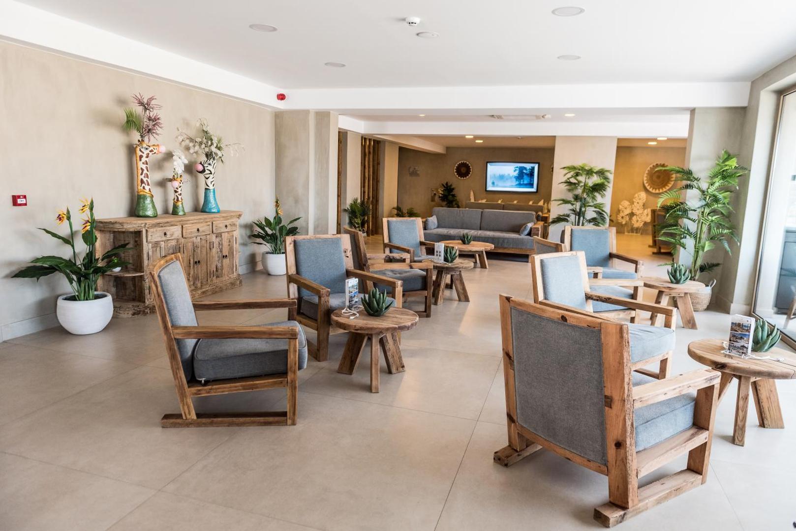 Pepper Sea Club viesnīcas lobby atpūtas telpa ar koka mēbelēm, pelēkiem krēsliem un dekoratīviem augiem podos