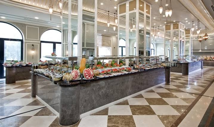 Ali Bay Resort Sorgun galvenā restorāna bufetes zona ar plašu ēdienu izvēli, dekoratīviem grebumiem un elegantu interjeru.
