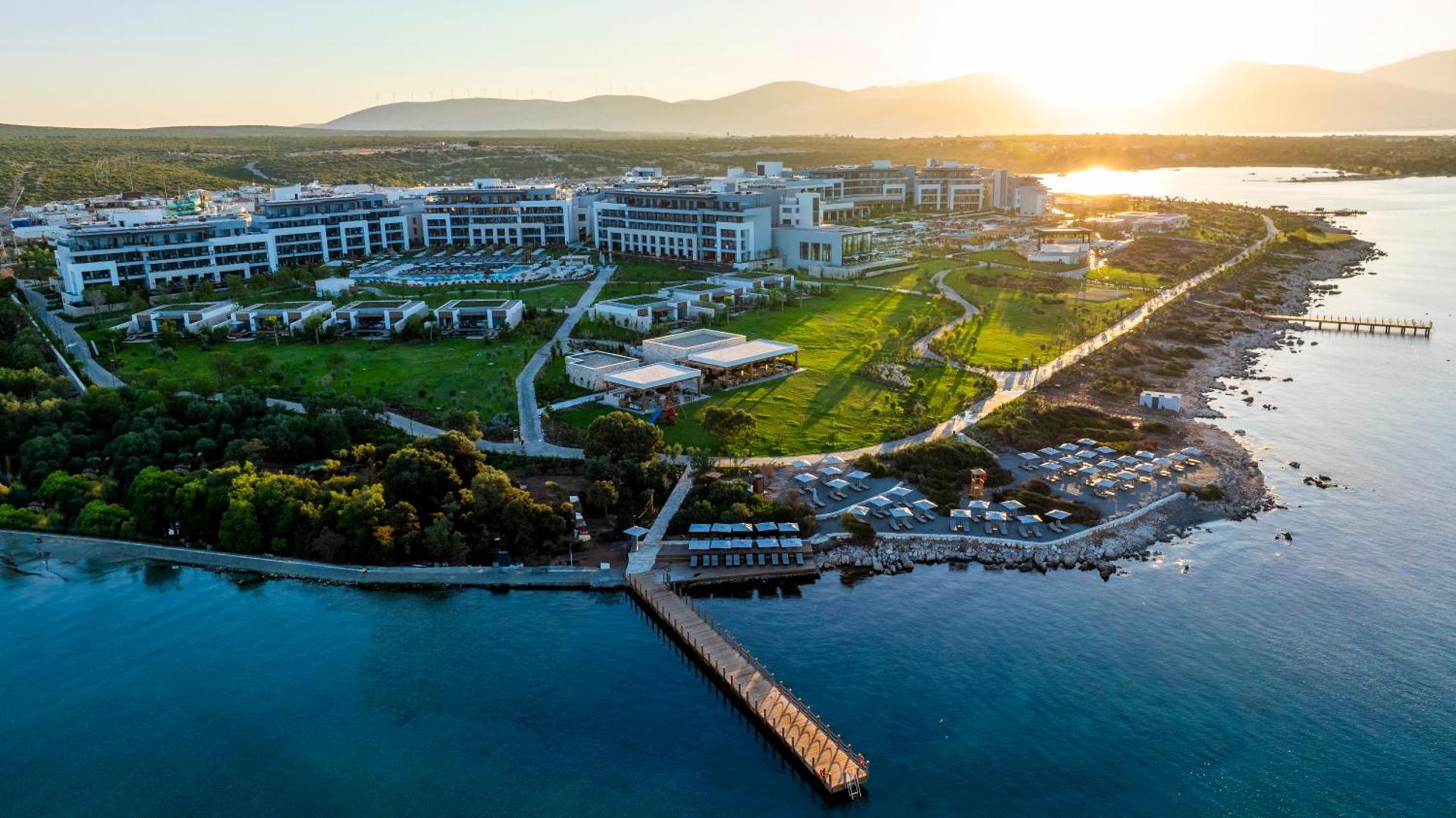 Anda Barut Collection viesnīcas panorāmas skats saulrietā Didimā — plaša teritorija pie Egejas jūras ar modernām ēkām un koka piestātni