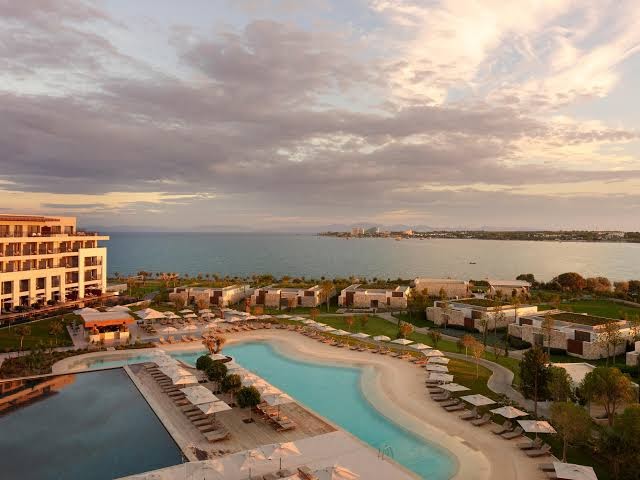 Anda Barut Collection panorāmas skats uz baseinu kompleksu un viesnīcas korpusiem saulrietā — plaša teritorija pie Egejas jūras