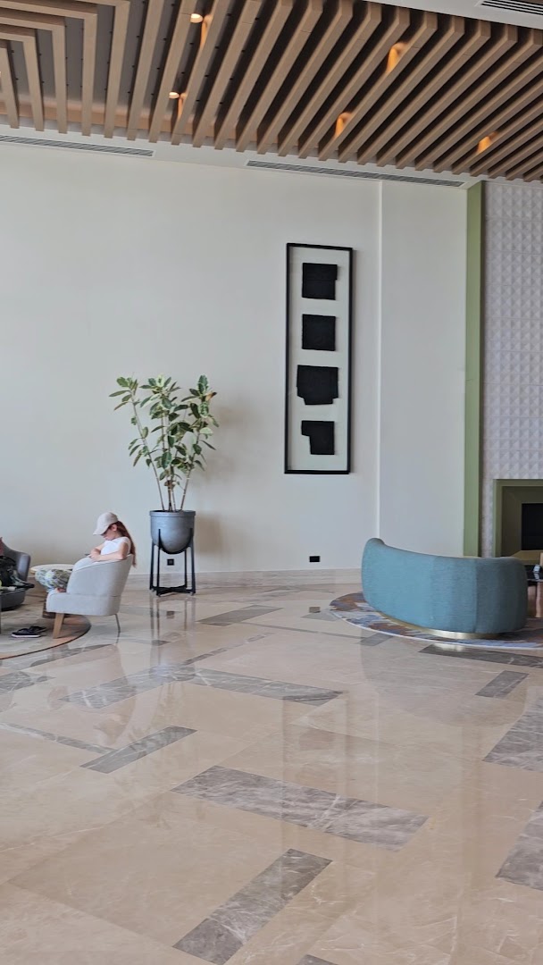 Anda Barut Collection viesnīcas vestibila interjera detaļa ar modernu mākslas darbu pie sienas, dekoratīvu augu un stilīgu atpūtas krēslu