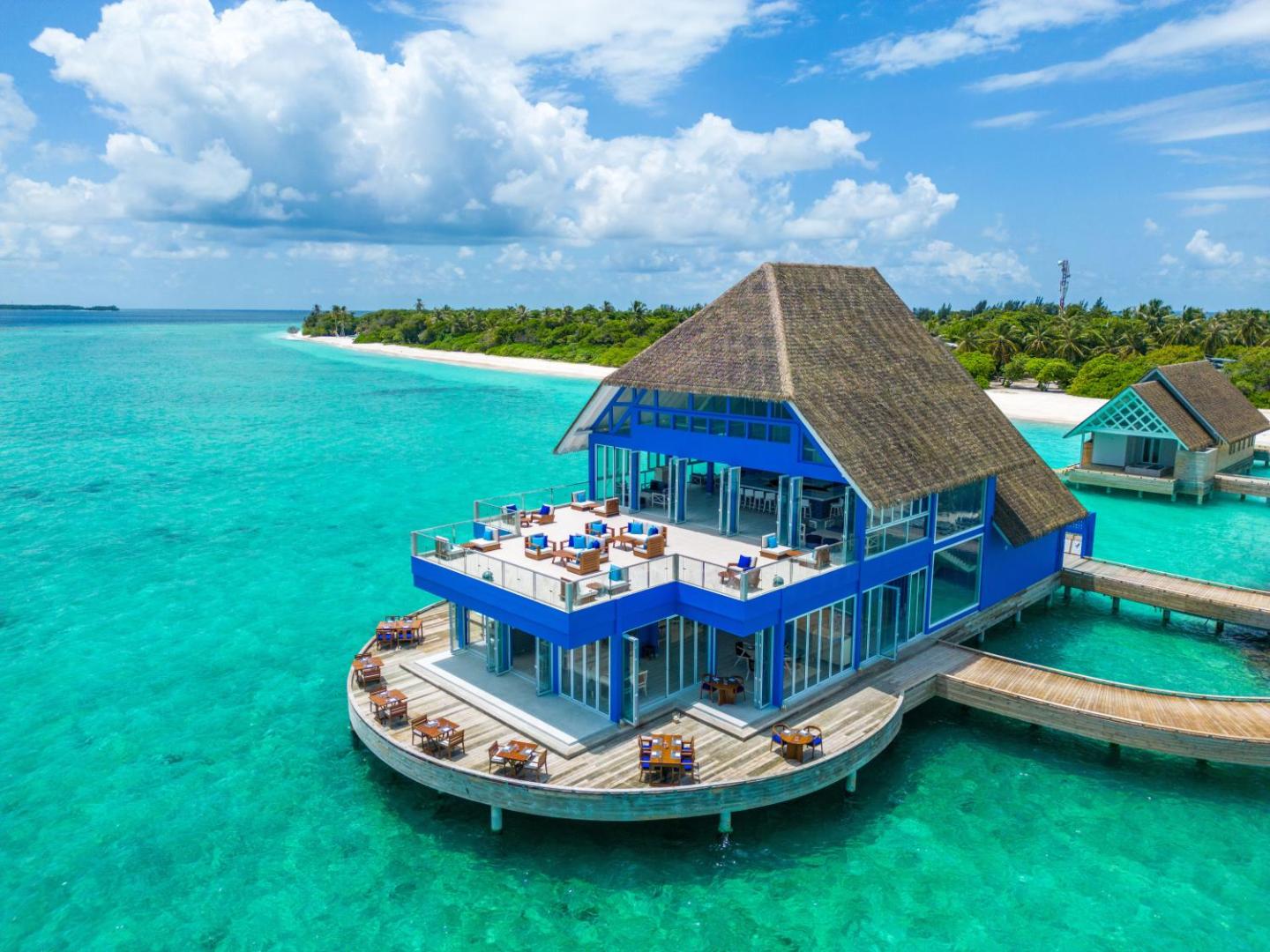 Ifuru Island Maldives kūrorta restorāns un bārs virs ūdens ar terasi, skats uz tirkīzzilo okeānu un balto smilšu pludmali