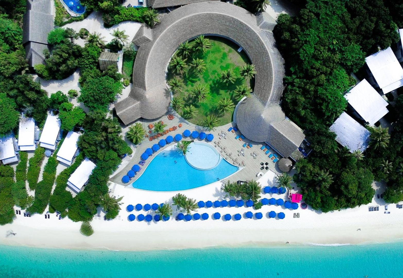 Ifuru Island Maldives kūrorta skats no putna lidojuma uz galveno baseinu, pludmali un unikālas formas ēkām palmu ielokā