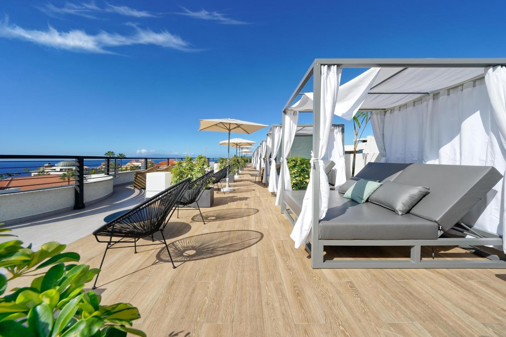 Hovima Suite Costa Adeje jumta terase ar ērtiem atpūtas zviļņiem, saulessargiem un skatu uz okeānu Tenerifes piekrastē