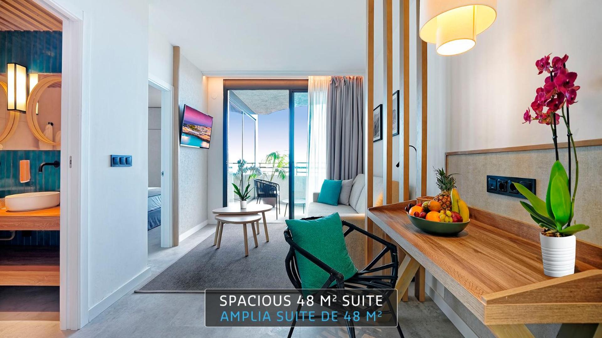 Hovima Suites Costa Adeje numura dzīvojamā zona ar dīvānu, balkonu, darba galdu un skatu uz vannasistabu
