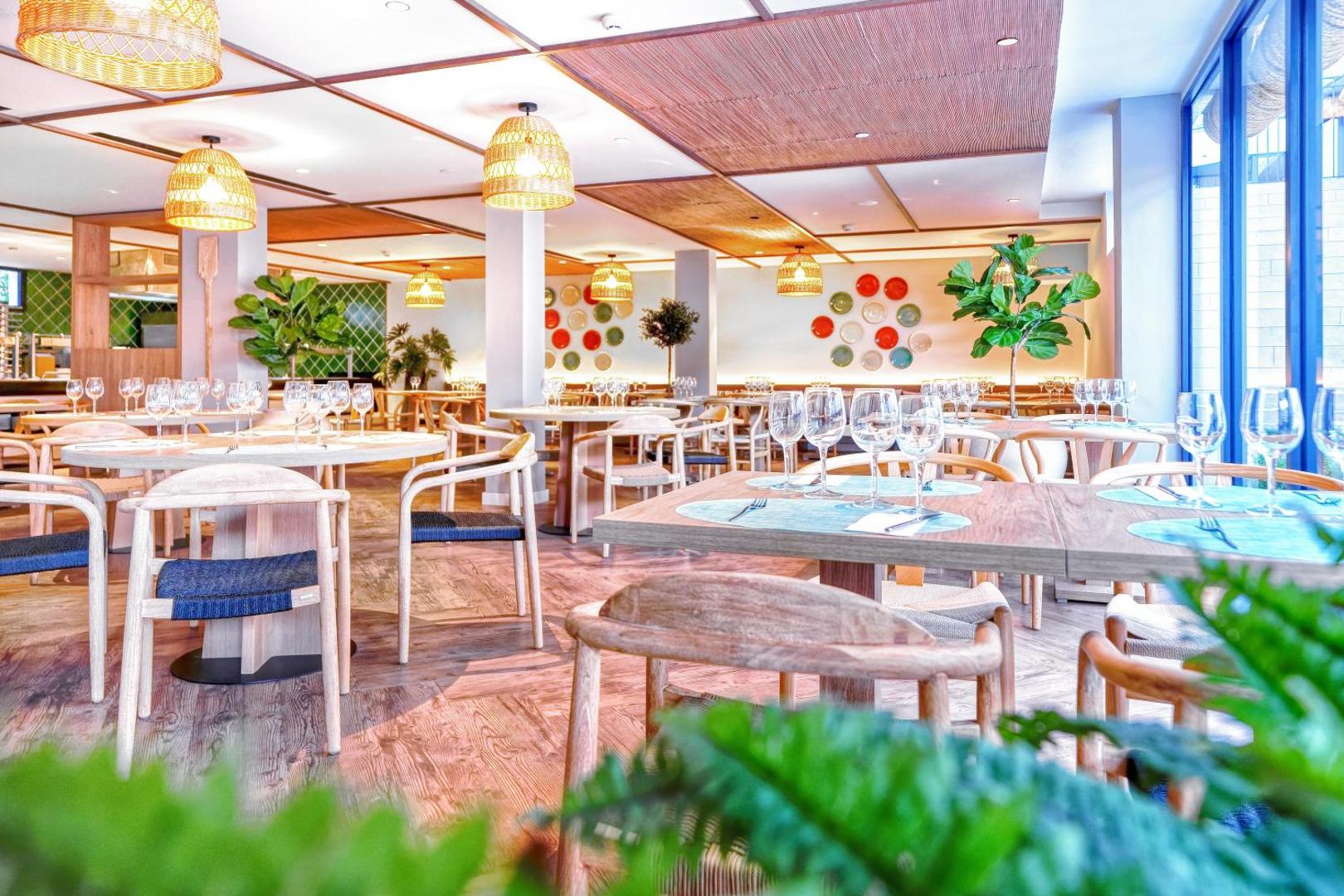 Hovima Suite Costa Adeje galvenais restorāns ar modernām koka mēbelēm, pītiem gaismekļiem un dekoratīviem šķīvjiem pie sienām Tenerifē