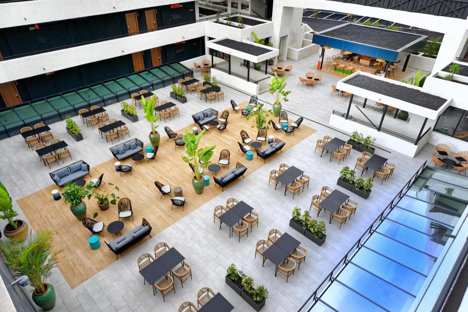 Hovima Suites Costa Adeje iekšpagalma terase no augšas — modernas sēdvietas, dīvāni un bārs atpūtai brīvā dabā