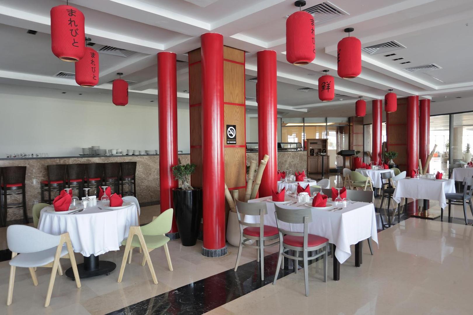 Xanadu Club Makadi Bay Āzijas virtuves ēdienkartes restorāns ar sarkaniem lukturiem un eleganti klātiem galdiem iekštelpās