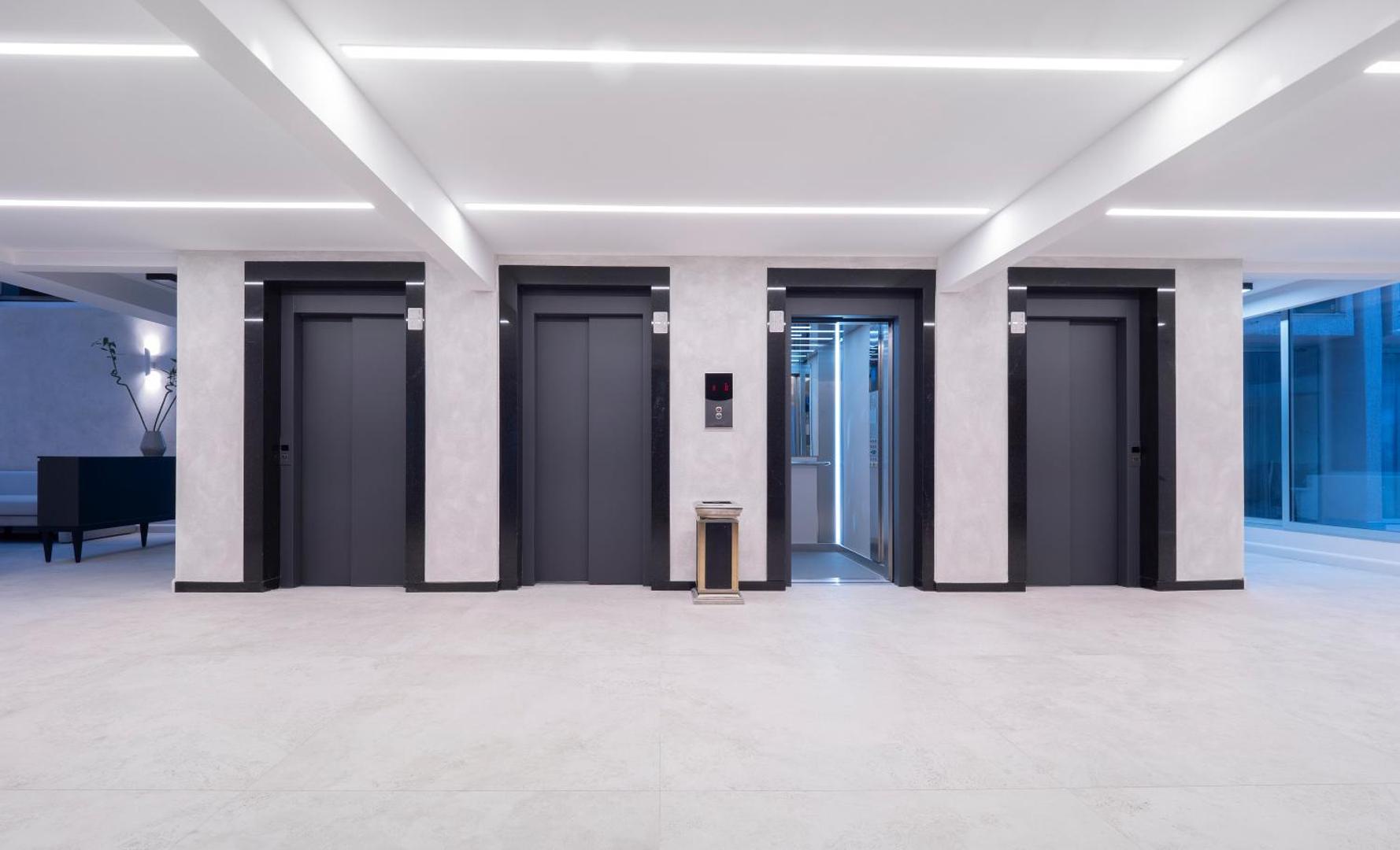 Hotel Tara modernais vestibils ar četriem elegantiem liftiem un gaišu interjeru Melnkalnes kūrortviesnīcā