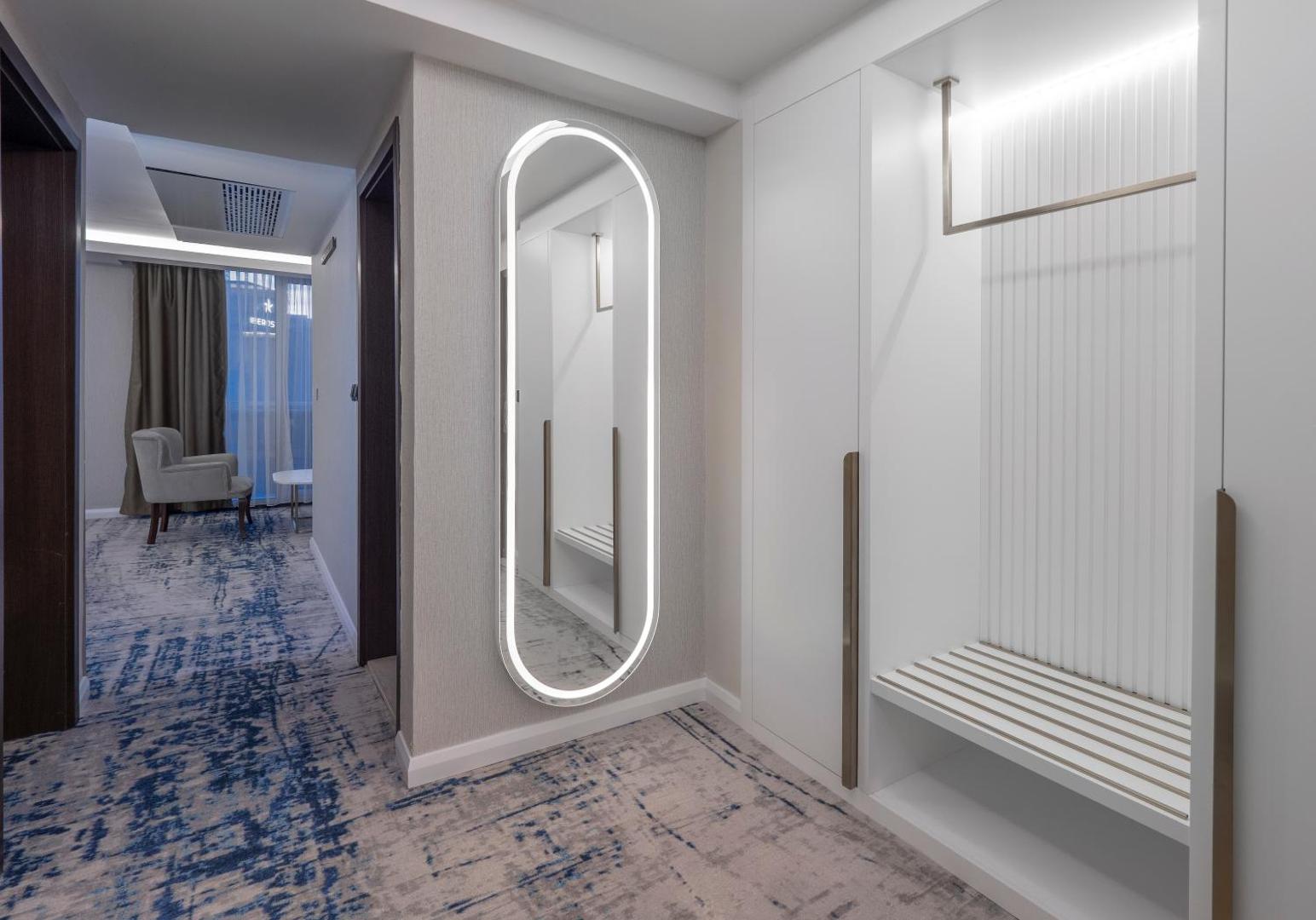 Hotel Tara numura priekšnams ar lielu spoguli un iebūvētu skapi — minimālistisks dizains un gaiši toņi viesnīcā Bečiči