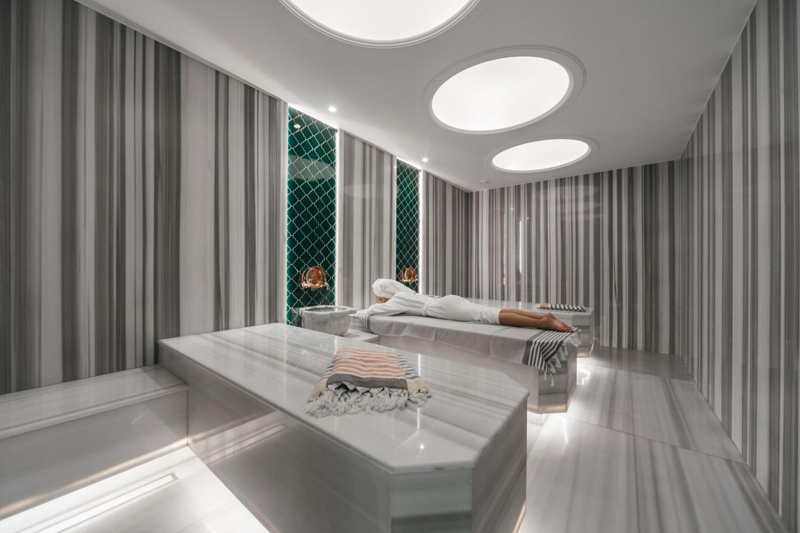 Mūsdienīgs un gaišs Hotel Tara spa procedūru numurs ar marmora galdiem un svītrainu sienu dizainu