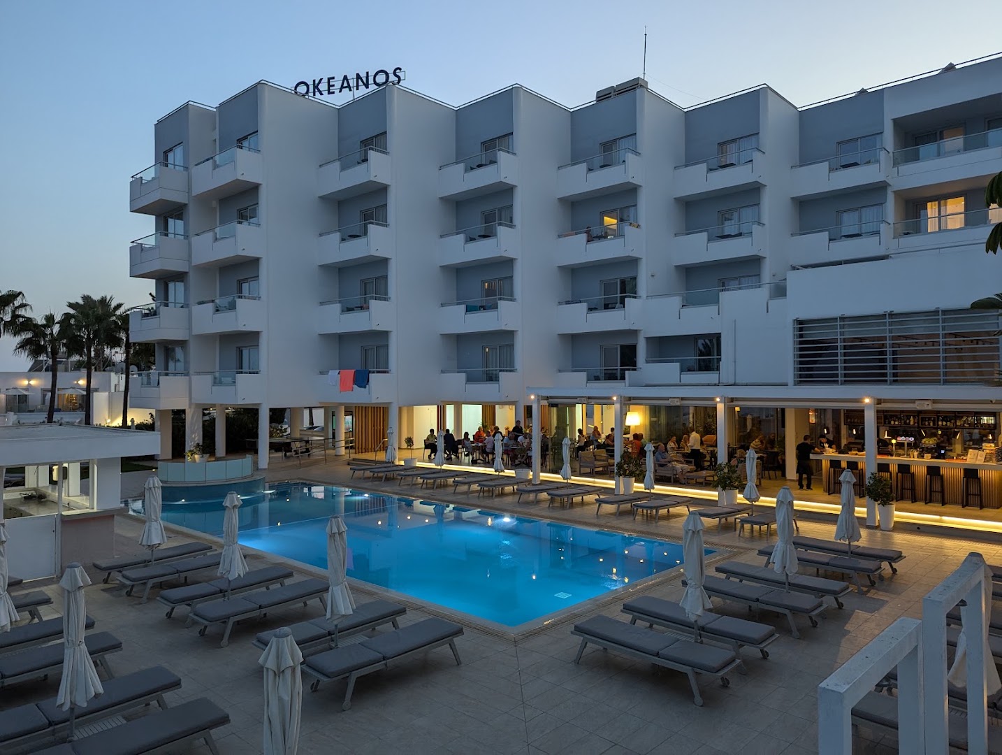 Okeanos Beach Boutique viesnīcas baseins un terase vakarā — izgaismota atpūtas zona ar bāru un restorānu Ajanapas piekrastē