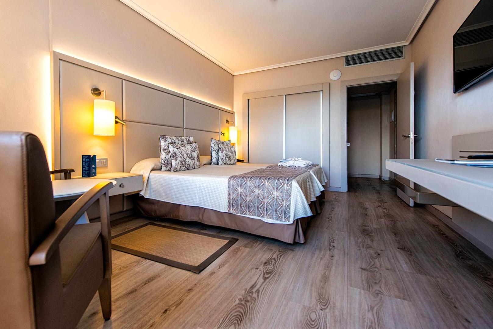 Arona Gran Hotel & Spa numura interjers ar divām gultām, iebūvēto skapi un modernu apgaismojumu siltos toņos