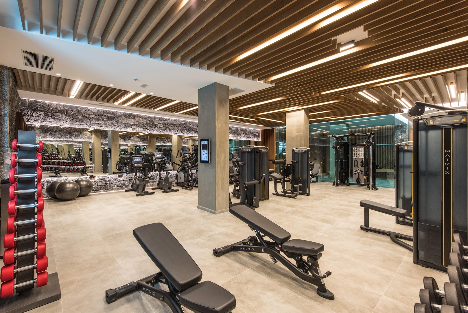 Nana Royal Premium Resort & Spa moderns fitness centrs ar Matrix trenažieriem, koka griestu apdari un plašu brīvo svaru zonu