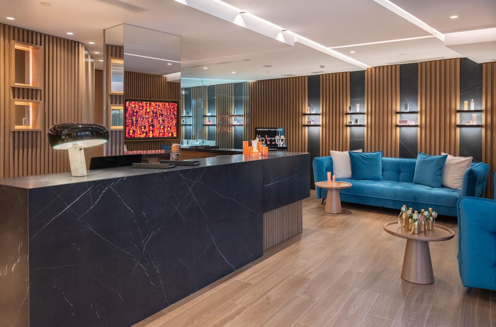 Nana Royal Premium Resort & Spa spa centra recepcija ar tumša marmora leti, koka sienu paneļiem un ziliem dīvāniem Hersonisā, Krētā