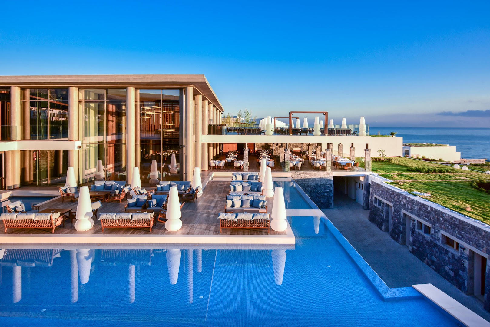 Nana Royal Premium Resort & Spa āra terase ar mīkstajiem dīvāniem pie baseina un skatu uz jūru saulrietā
