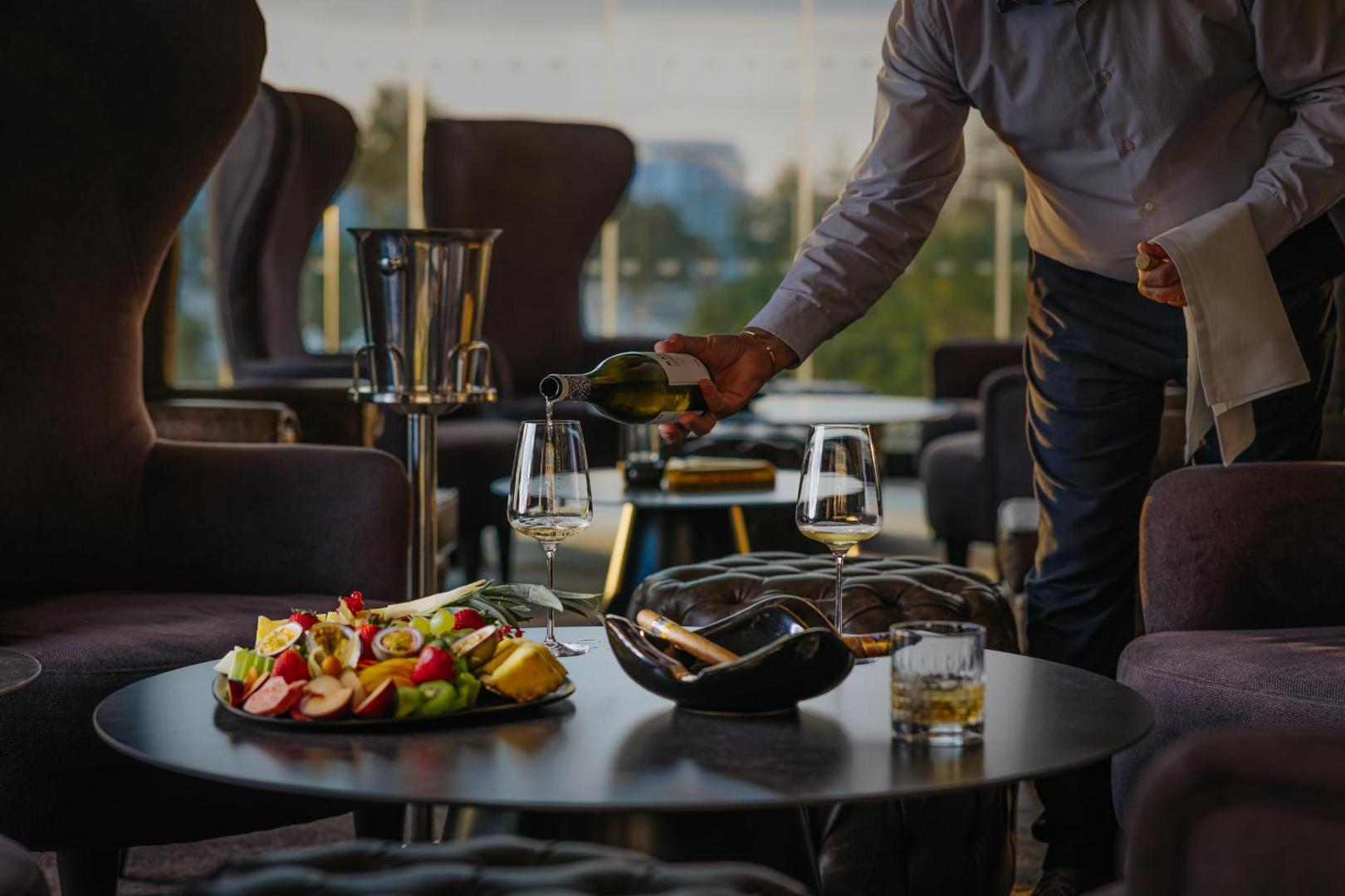 Nissiblu Beach Resort atpūtas telpa ar vīna pasniegšanu, augļu plati un cigāriem — elegants interjers ar mīkstajiem atpūtas krēsliem Aijanapā.