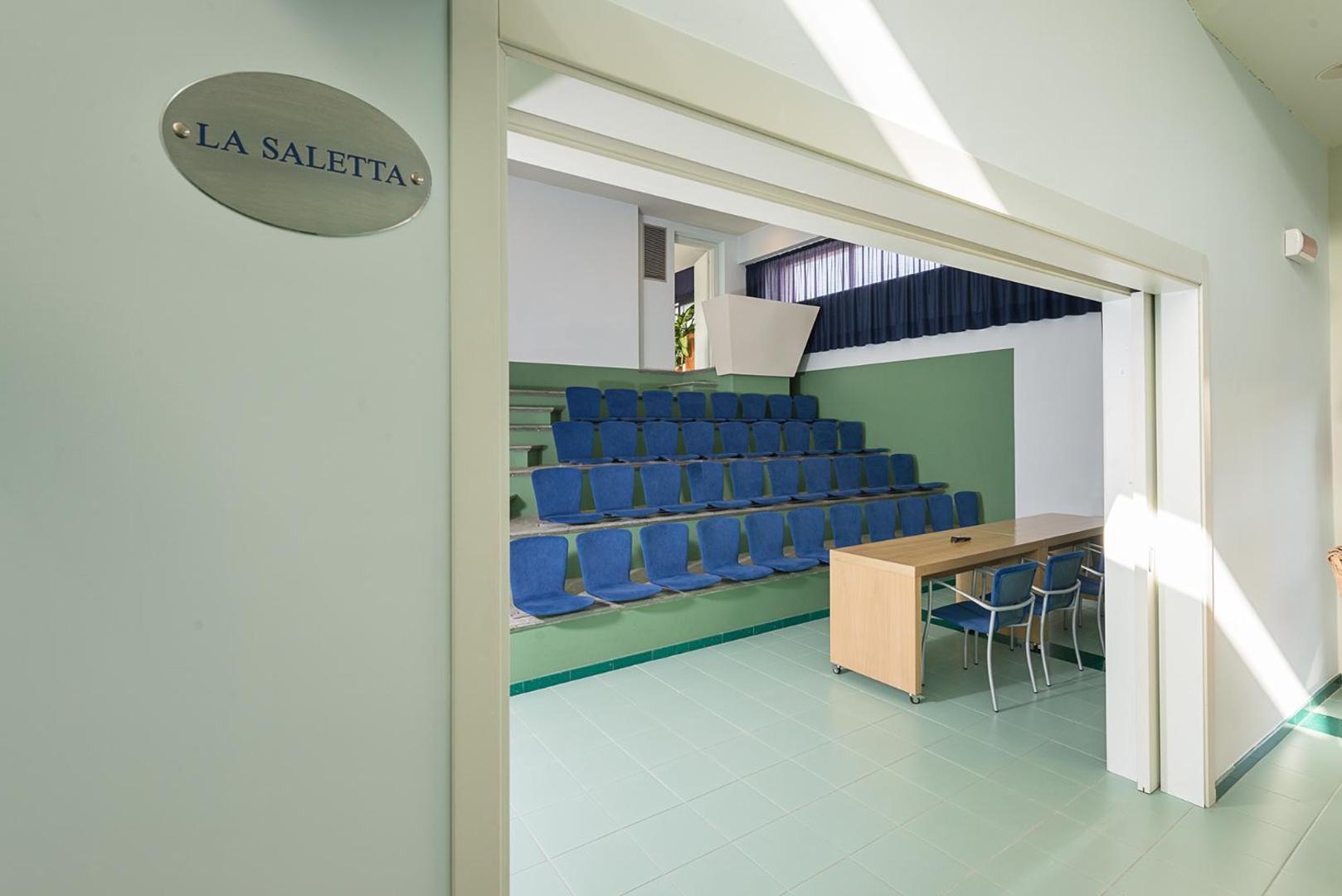 Mazāka sanāksmju telpa La Saletta viesnīcā Rada Siri Hotel ar amfiteātra tipa sēdvietām un koka galdu