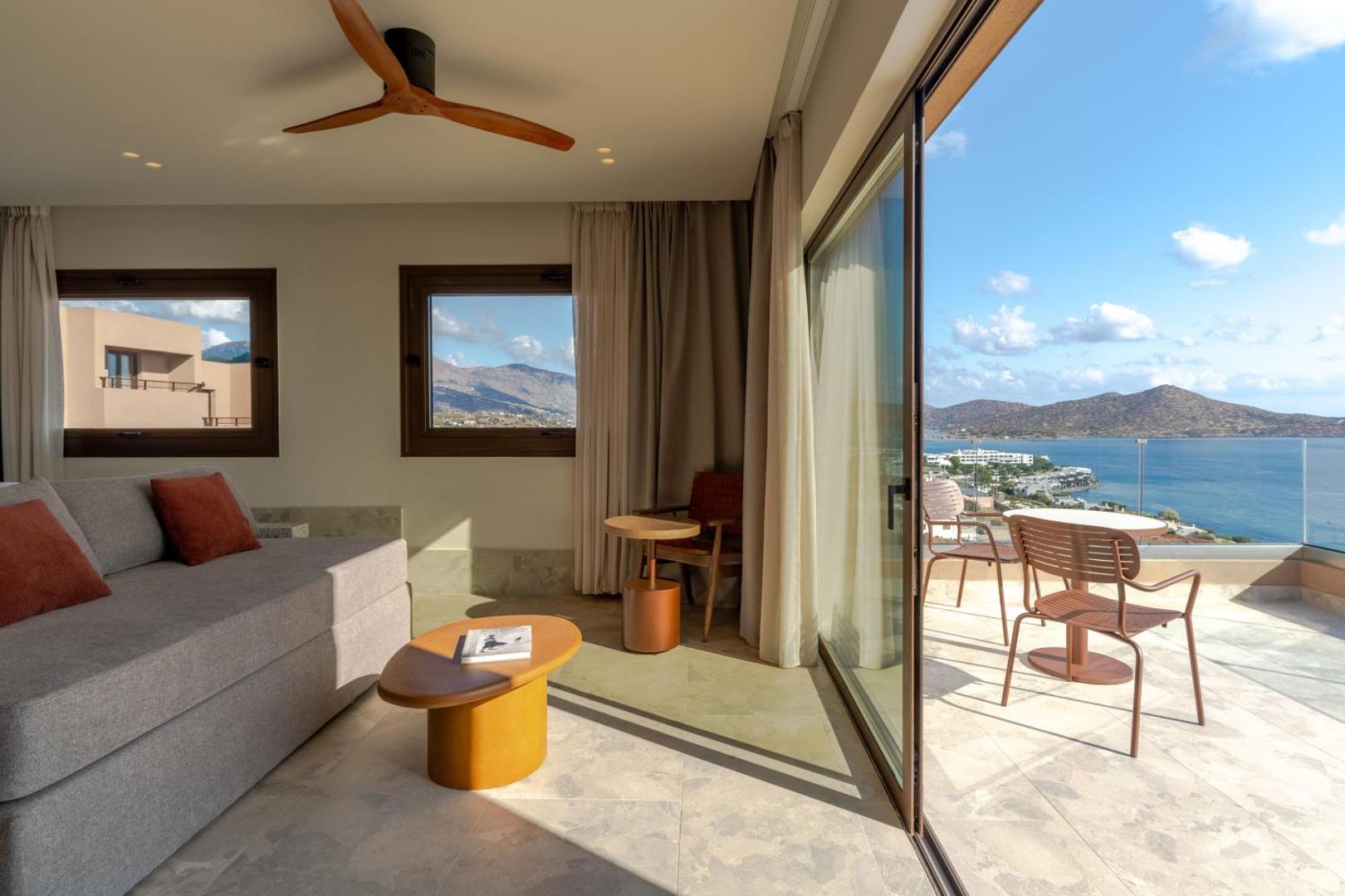 Skats no INNSiDE by Meliá Elounda numura terases uz jūras līci un kalniem, atpūtas krēsli un galdiņš uz balkona