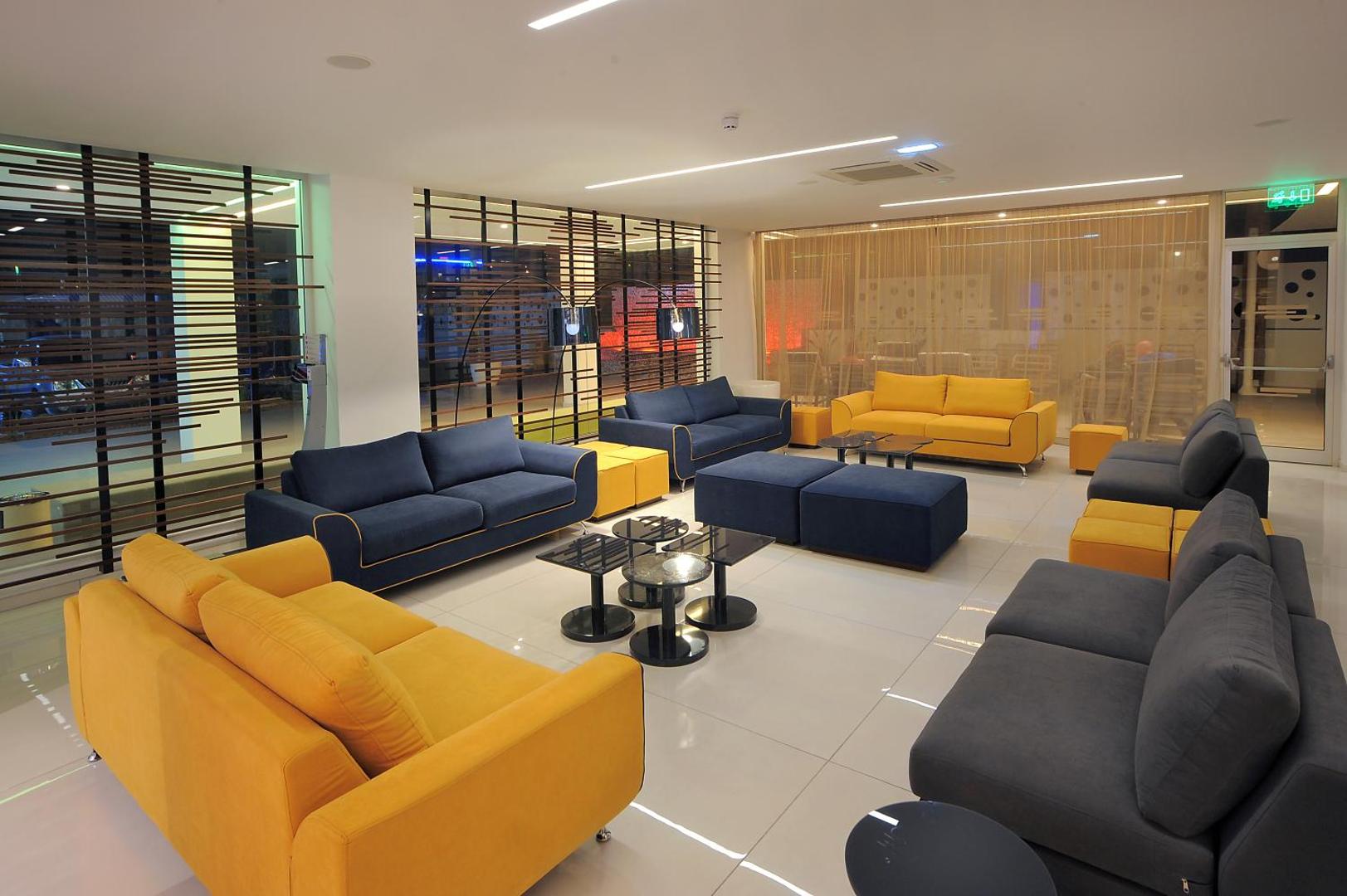 Nelia Beach viesnīcas lobby atpūtas zona ar košiem dzelteniem un tumši ziliem dīvāniem mūsdienīgā interjerā