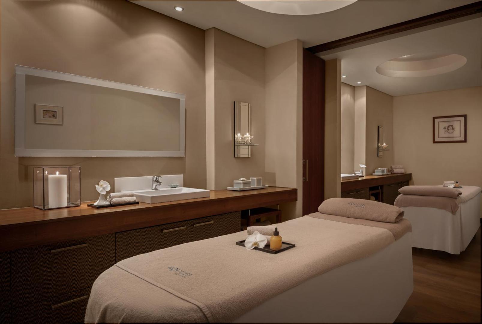 Mediterranean Beach Hotel spa centra procedūru telpa ar divām masāžas gultām, siltu apgaismojumu un relaksējošu atmosfēru.