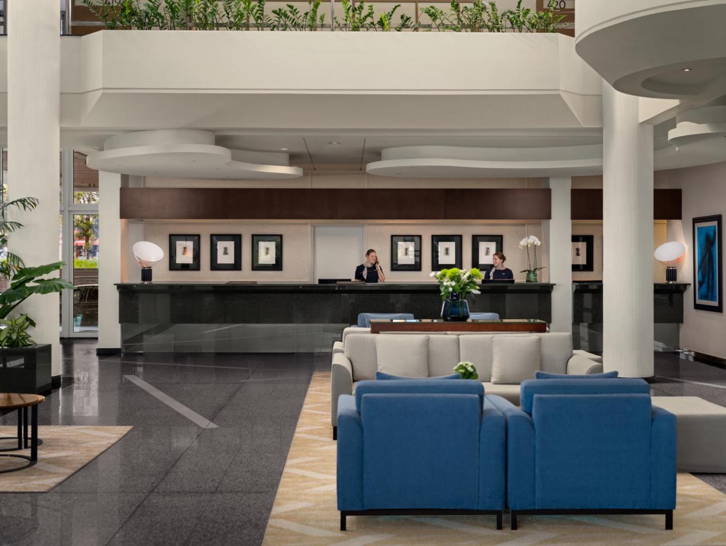 Mediterranean Beach Hotel galvenā recepcija un vestibils ar moderniem ziliem dīvāniem, augstiem griestiem un viesmīlīgu personālu.