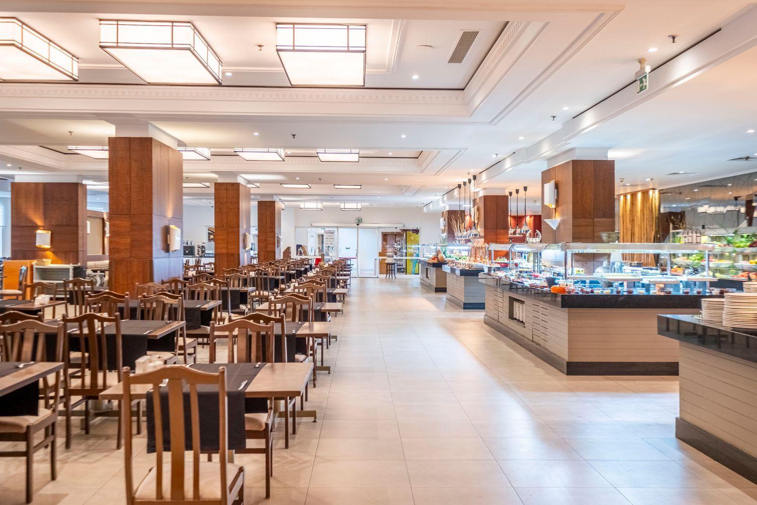 Plašs viesnīcas iekštelpu restorāns ar bagātīgu bufetes līniju un koka interjera elementiem.