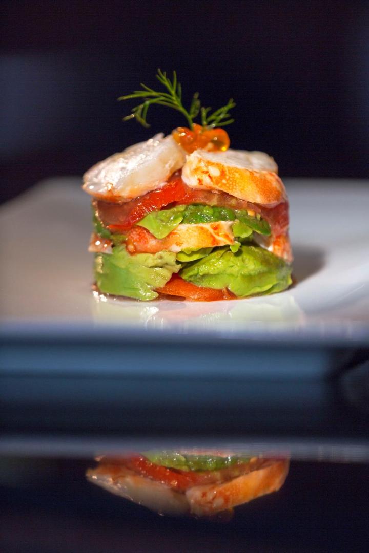 Smalki noformēta jūras velšu un avokado uzkoda ar kaviāru uz balta šķīvja.