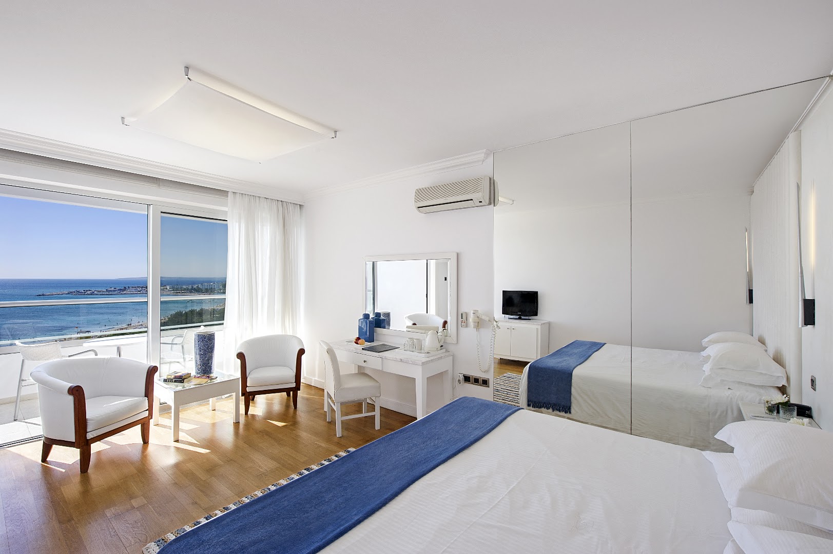 Grecian Sands viesnīcas numurs ar skatu uz jūru Aijanapā, Kiprā — gaišs interjers, atpūtas krēsli un balkons ar panorāmas skatu