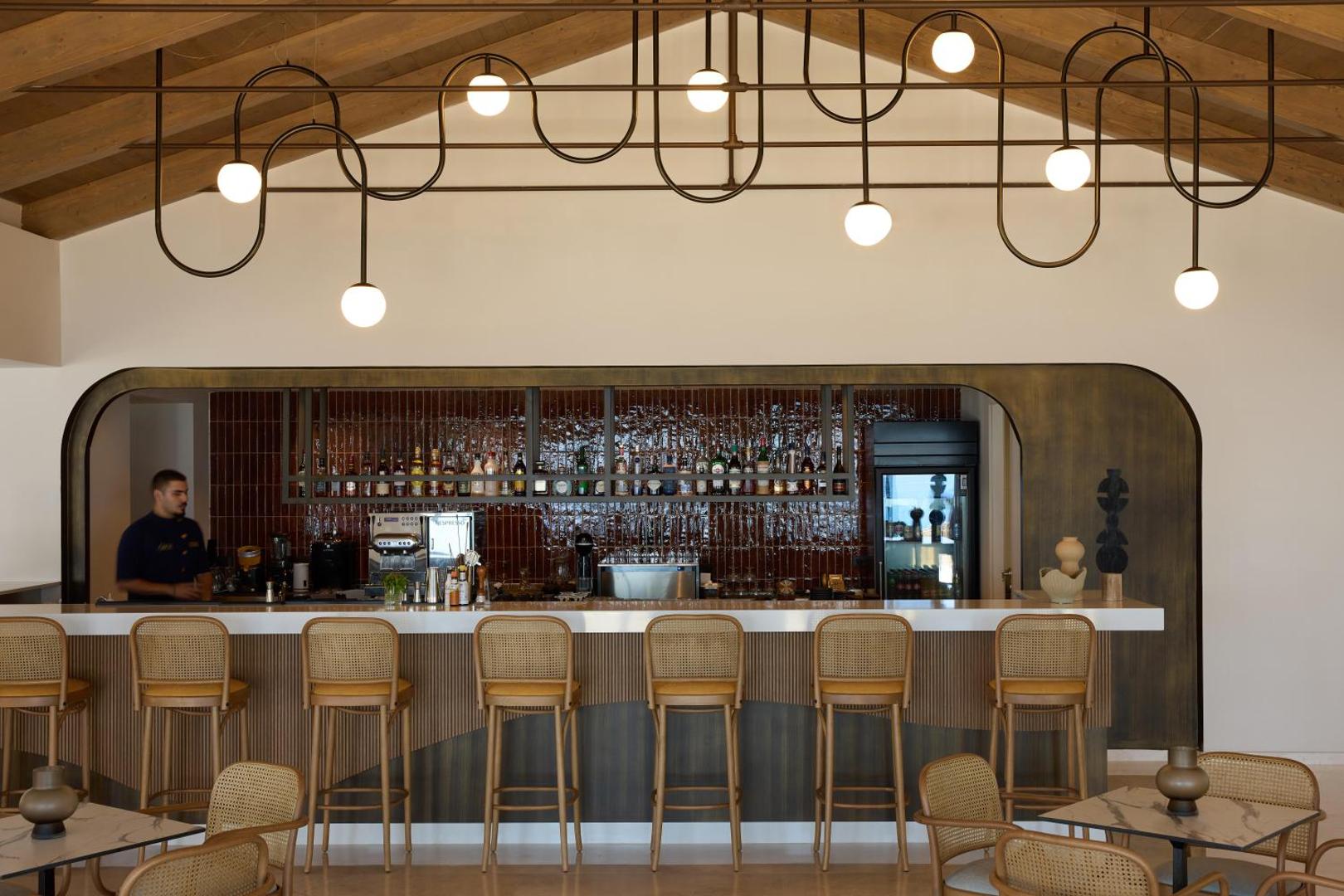 Eleganta bāra lete ar augstiem krēsliem un unikālu, modernu apgaismojumu pie griestiem.