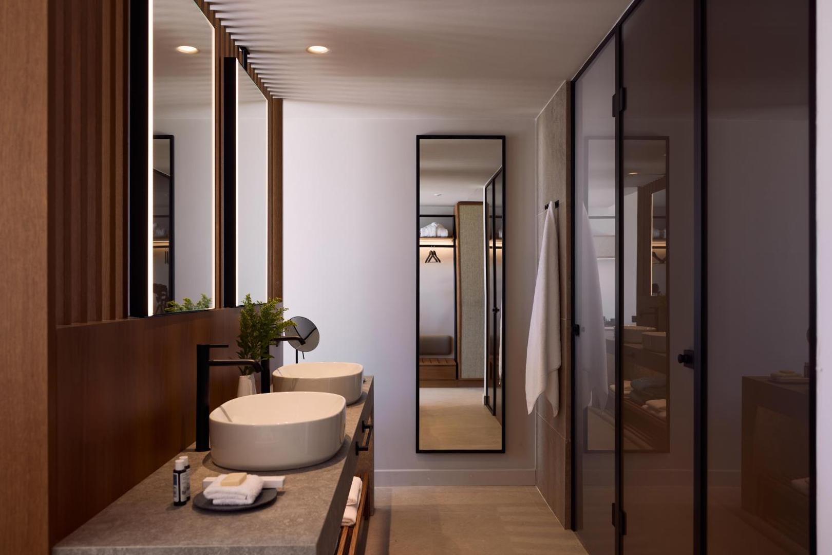 Gaiša un plaša vannas istaba ar akmens virsmām, koka elementiem un stikla durvīm.