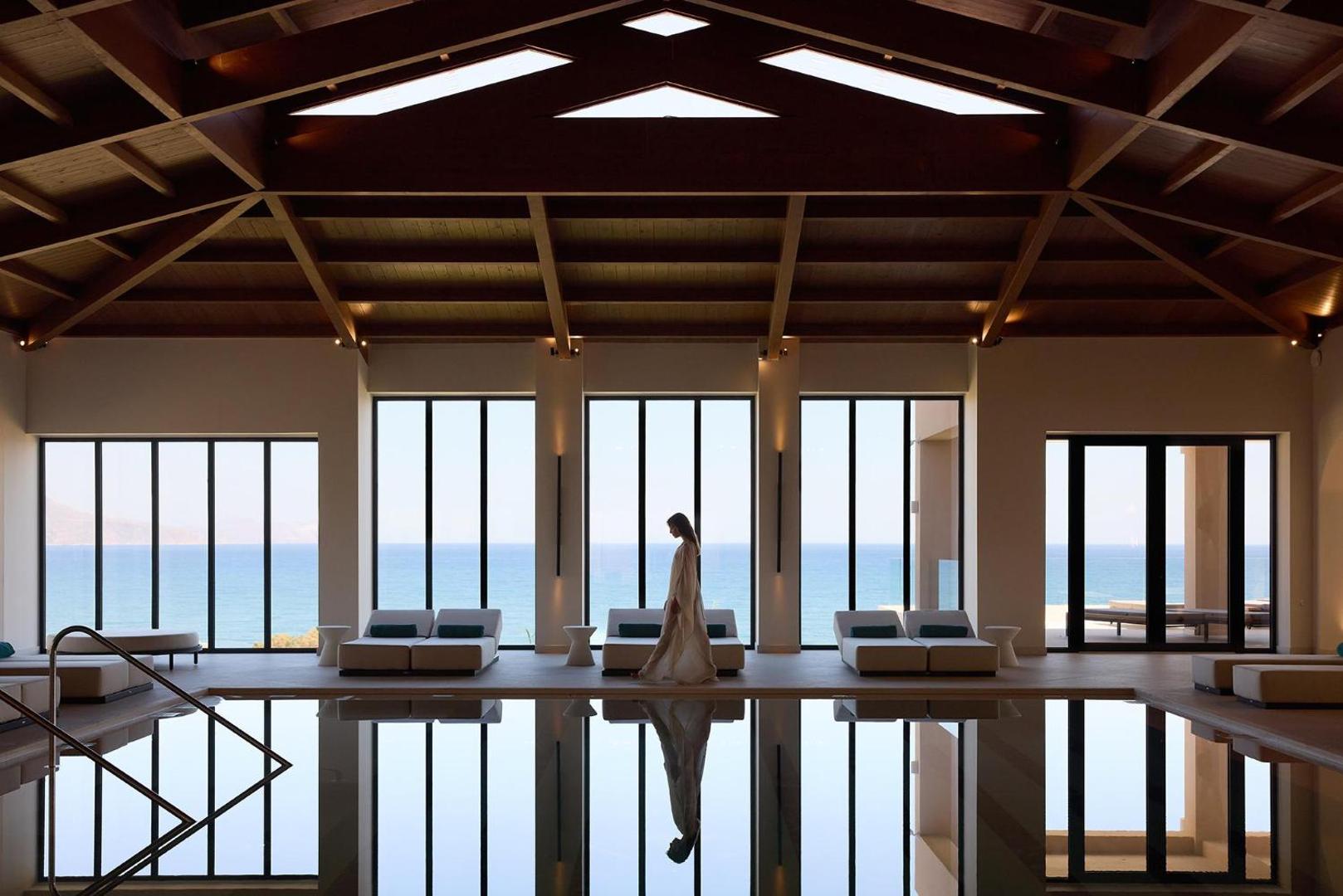 Iekštelpu baseins ar lieliem logiem uz jūru un koka siju griestiem.