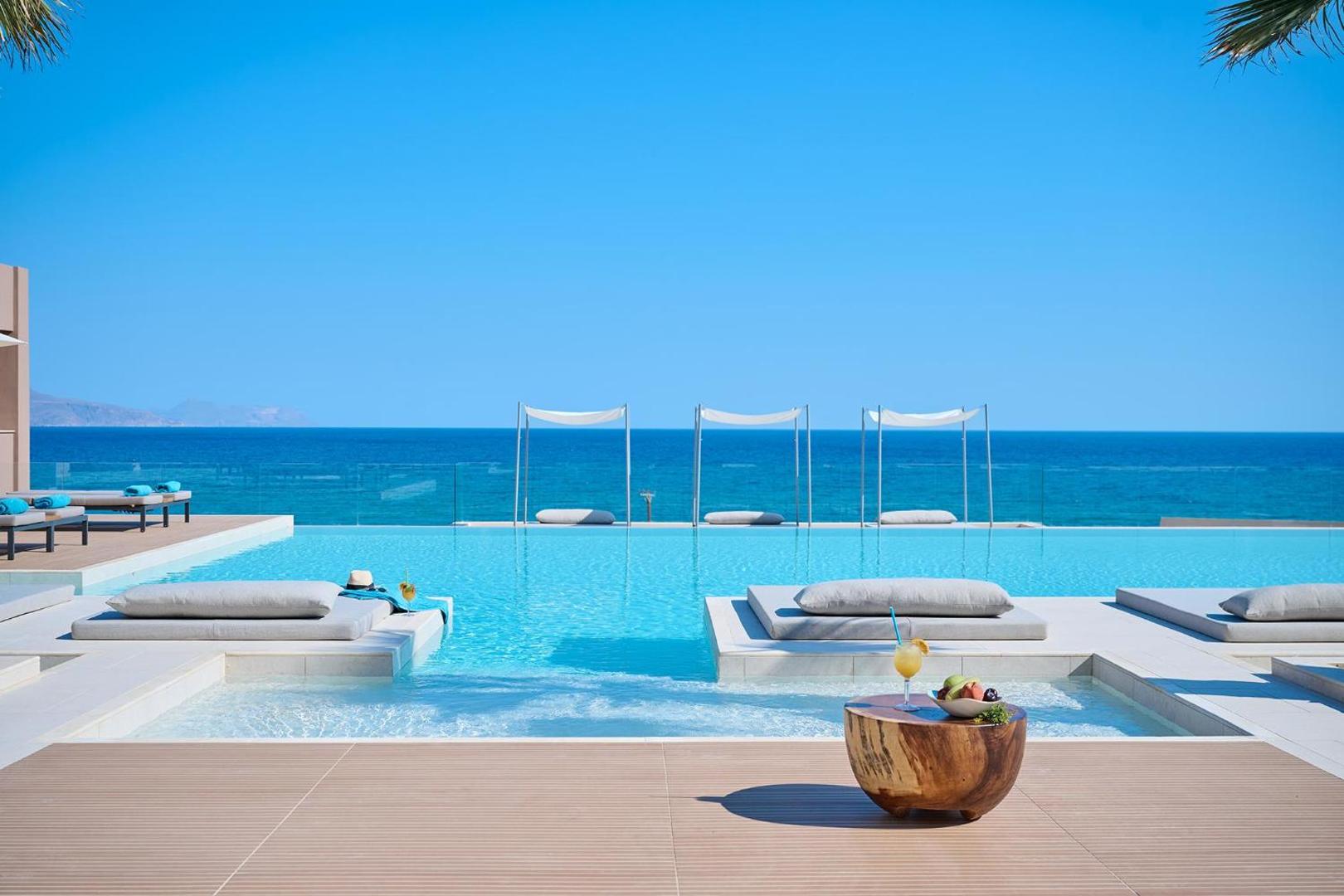 Bezgalības baseins ar skatu uz zilajiem Krētas jūras ūdeņiem un saulainām debesīm.