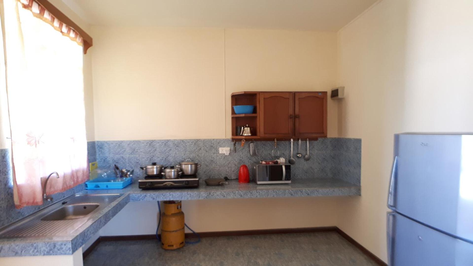 Virtuves zona ar zilu darba virsmu, gāzes plīti, mikroviļņu krāsni un ledusskapi.