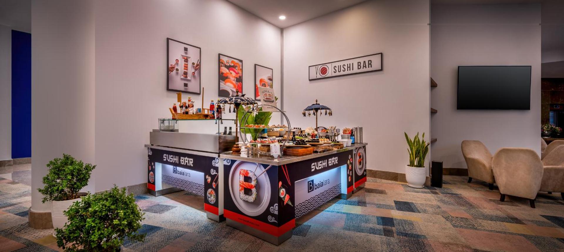 Mūsdienīgs suši bārs viesnīcas iekštelpās ar krāsainu dekoratīvo apdari un atpūtas zonu.