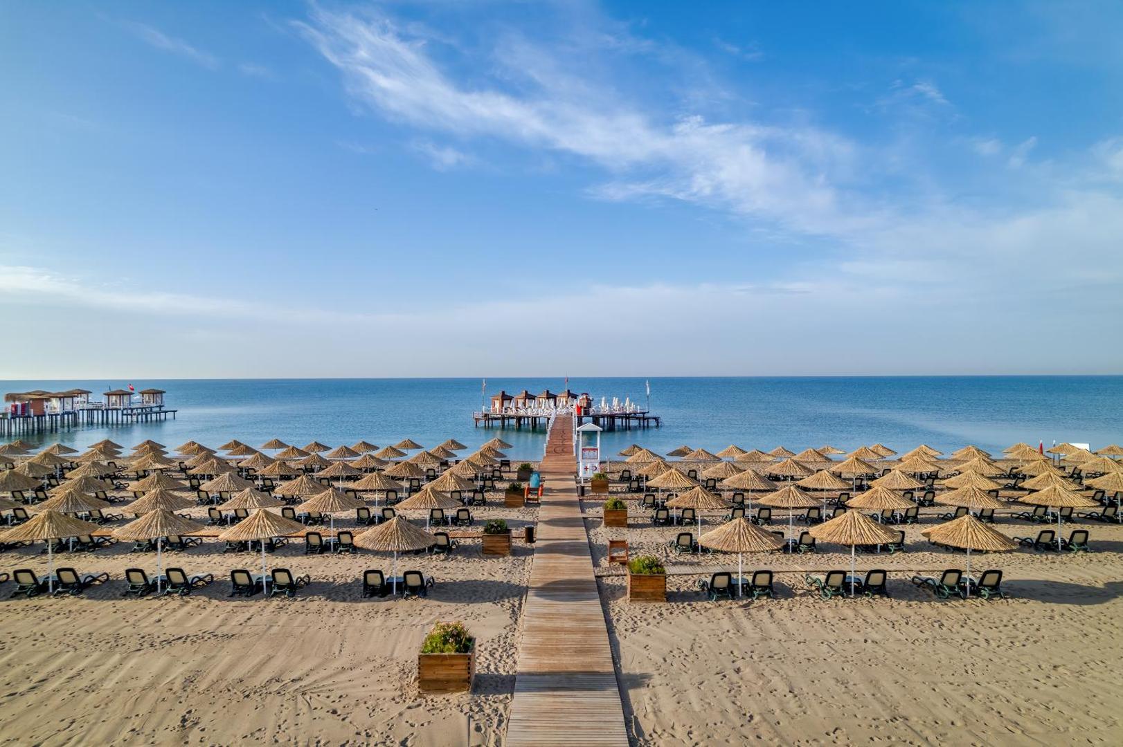 Koka laipa ved cauri saulessargu rindām uz Baia Lara piestātni jūrā.