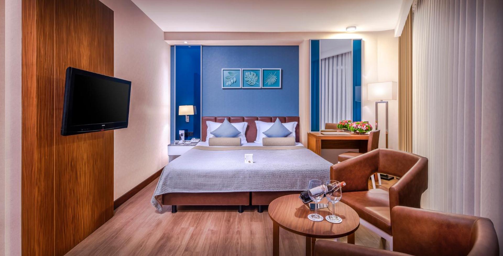 Viesnīcas numura interjers ar atpūtas zonu, kurā ir divi ādas krēsli un galdiņš.