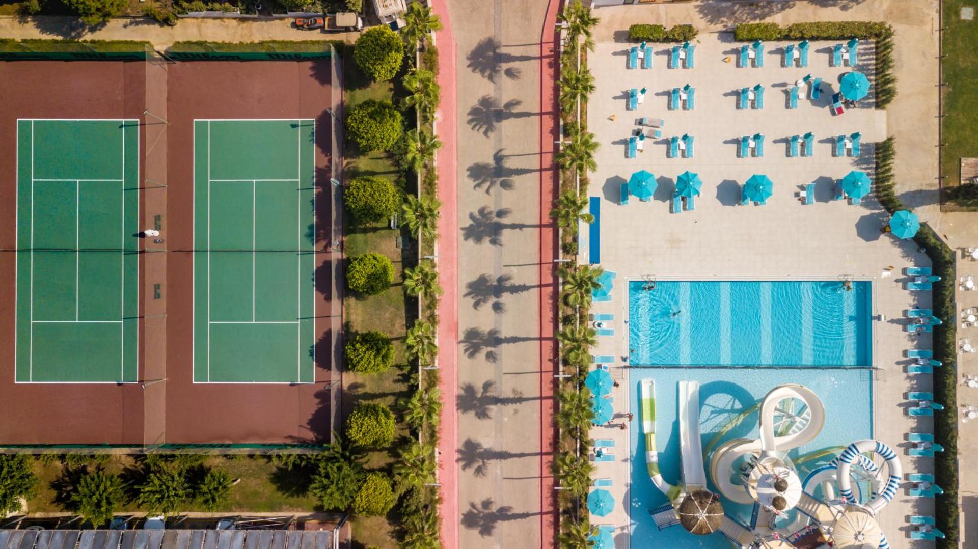 Aerofoto skats uz Baia Lara tenisa kortiem, baseinu ar slidkalniņiem un palmu aleju.