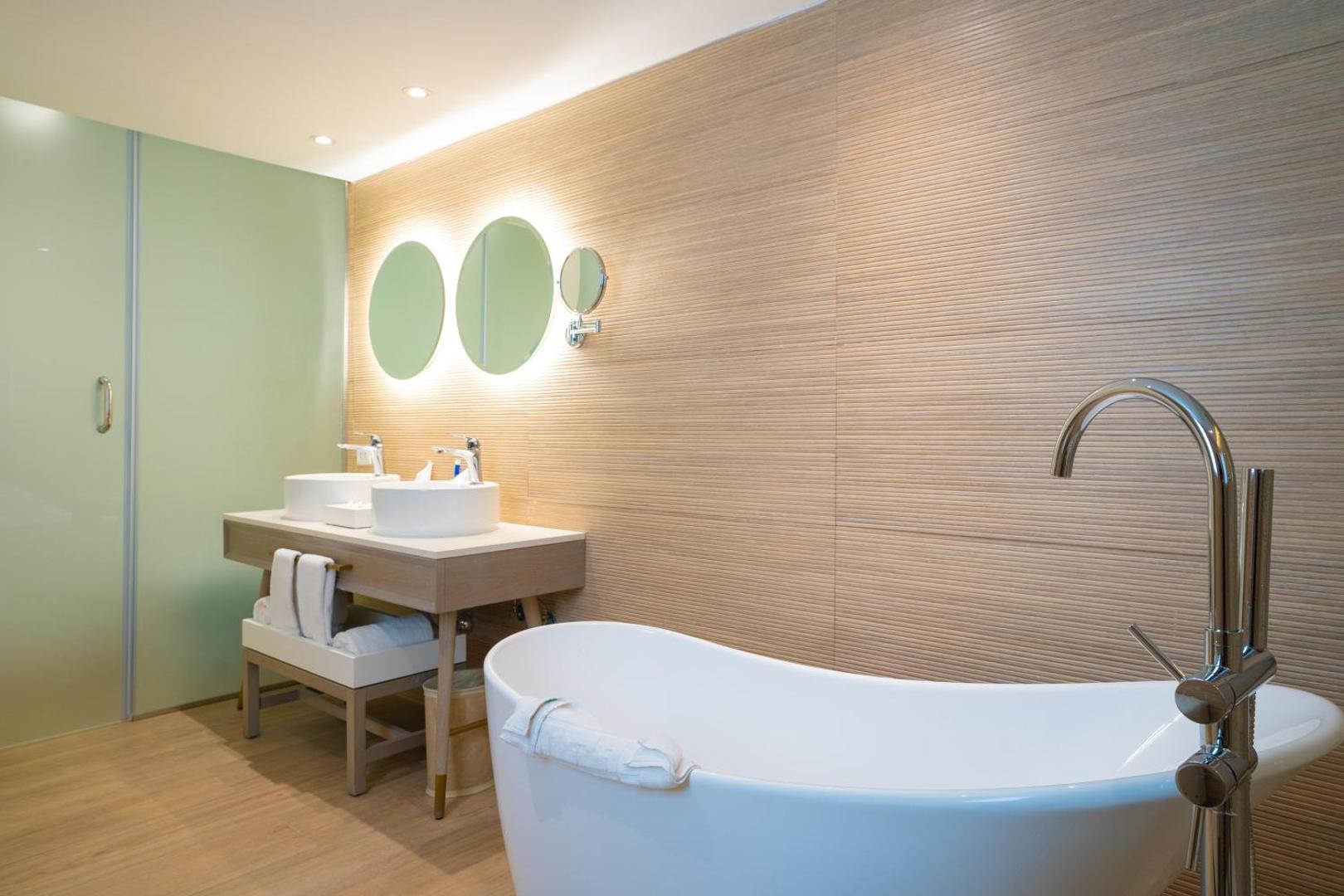 Gaiša vannas numura interjers ar brīvstāvošu vannu un divām izlietnēm.